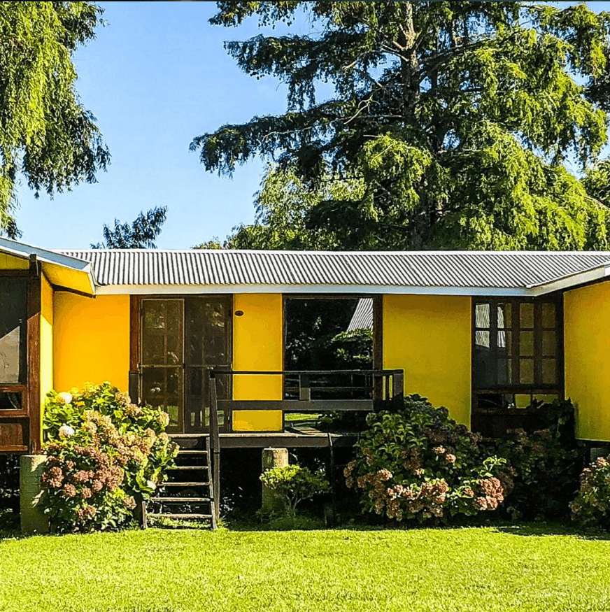 Galería y frente de una cabaña con hortensias en flor