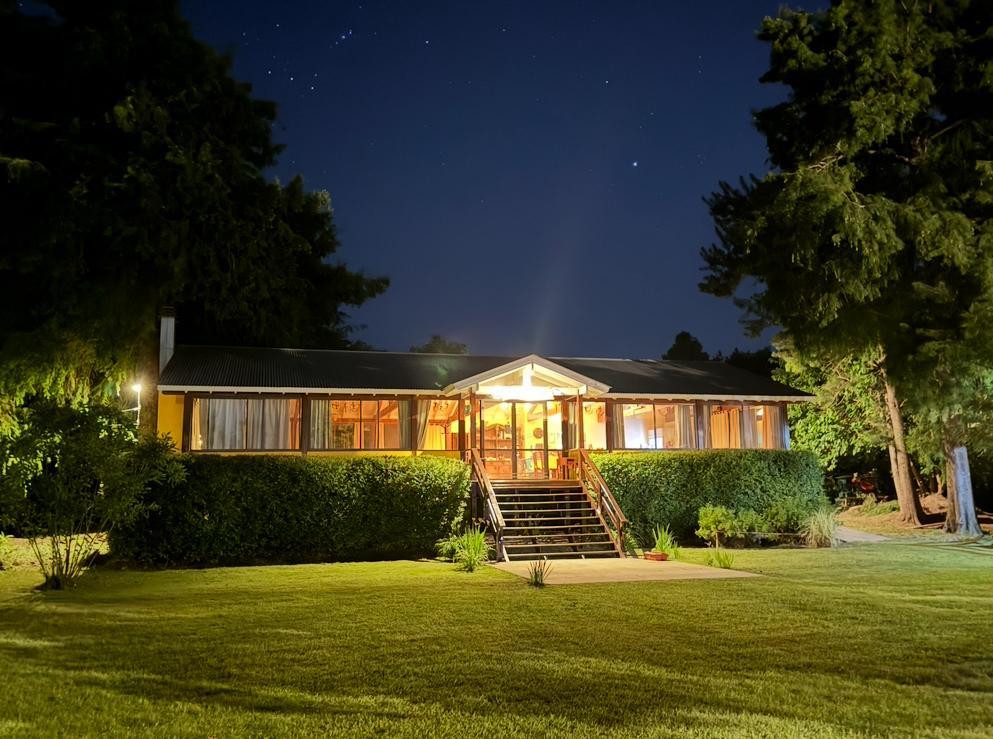 La casa principal iluminada de noche, bajo un cielo estrellado